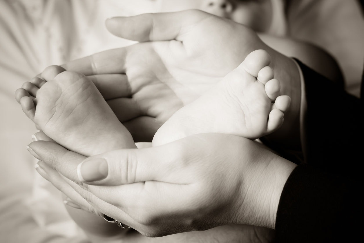 Mother gently holding the feet of her newborn baby